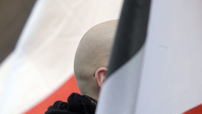 Extremismus - Dresden: En Mann mit geschorenem Kopf steht zwischen schwarz-weiß-roten Fahnen. Foto: picture alliance / dpa/Symbolbild