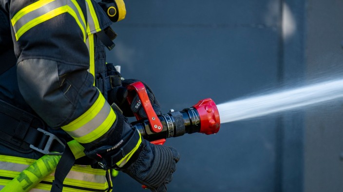 Brände - : Ein Mitglied der Feuerwehr spritzt aus einem Schlauch mit Wasser. Foto: David Inderlied/dpa/Symbolbild