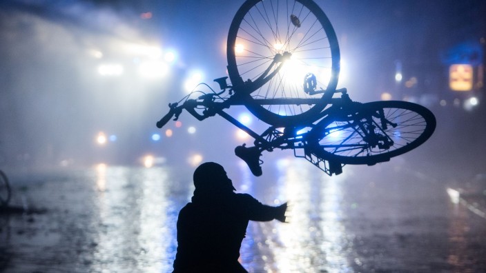 G20 - Hamburg: Ein Randalierer wirft im Schanzenviertel ein Fahrrad in Richtung von Wasserwerfern. Foto: Daniel Bockwoldt/dpa/Archivbild