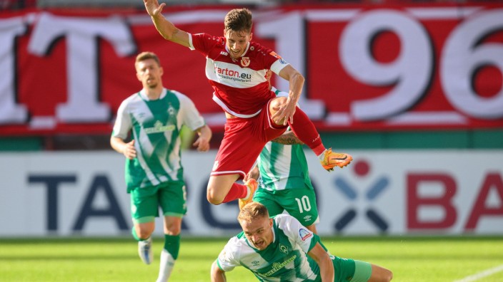 Fußball - Cottbus: Der Cottbuser Axel Borgmann springt über Bremens Amos Pieper. Foto: Robert Michael/dpa