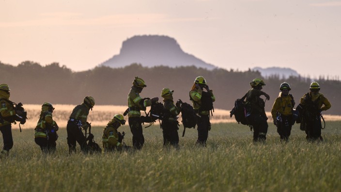 Brände - Bad Schandau: Feuerwehrleute stehen nach dem Einsatz im Nationalpark Sächsische Schweiz auf einer Wiese. Foto: Robert Michael/dpa/Archivbild