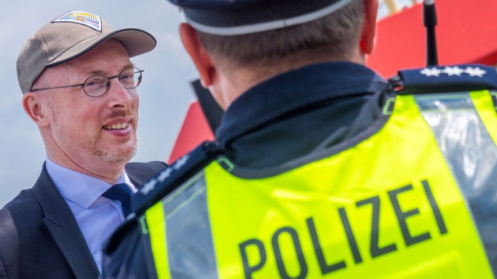 Polizei - Schwerin: Mecklenburg-Vorpommerns Innenminister Christian Pegel (SPD, l) spricht mit einem Polizisten. Foto: Jens Büttner/dpa/Archivbild