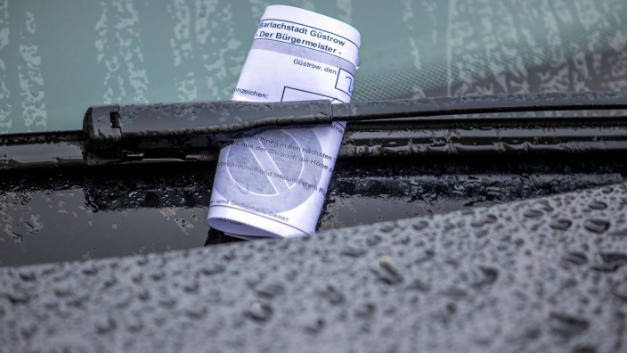 Verkehr - Schwerin: Ein Knöllchen steckt bei Regen unter dem Scheibenwischer eines Autos, das falsch geparkt wurde. Foto: Jens Büttner/dpa-Zentralbild/dpa/Symbolbild