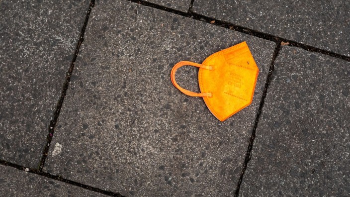 Landtag - Kiel: Ein gebrauchter orangefarbener Mund-Nasen-Schutz liegt auf dem Gehweg. Foto: Peter Kneffel/dpa/Symbolbild