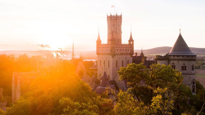 Wetter - Braunschweig: Die aufgehende Sonne taucht die Wälder und Schloss Marienburg am Morgen in warmes Licht. Foto: Julian Stratenschulte/dpa