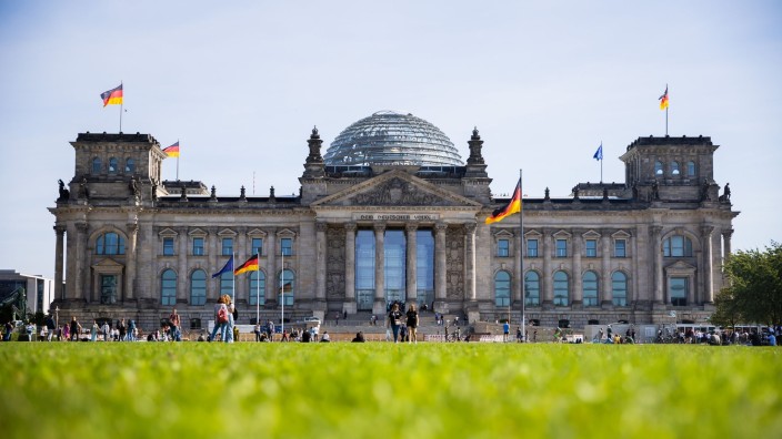 Wirtschaft - Berlin: Vor und auf dem Reichstagsgebäude wehen Deutschlandfahnen. Foto: Christoph Soeder/dpa/Archivbild
