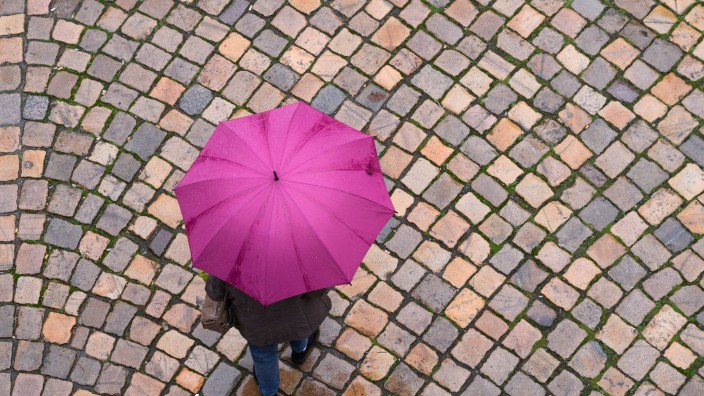 Wetter - Offenbach am Main: Eine Frau geht mit einem Regenschirm auf einer Straße entlang. Foto: Sebastian Kahnert/dpa-Zentralbild/dpa/Symbolbild