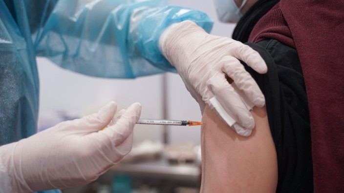 Gesundheit - Berlin: Ein Mitarbeiter eines Impfzentrums impft einen Mann gegen Corona. Foto: Jörg Carstensen/dpa/Symbolbild