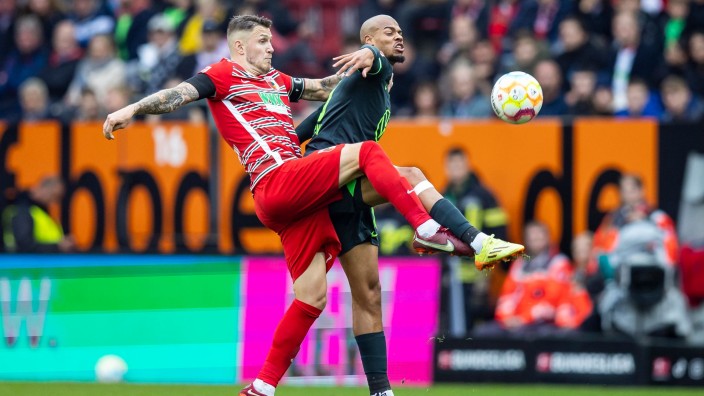 Fußball - Augsburg: Augsburgs Jeffrey Gouweleeuw (l) in Aktion gegen Wolfsburgs Lukas Nmecha (r). Foto: Tom Weller/dpa