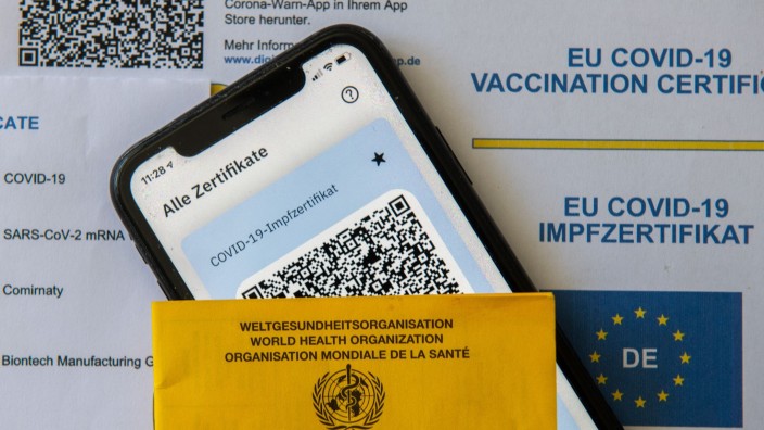 Prozesse - Bielefeld: Ein Impfpass und ein Smartphone mit der CovPass-App liegen auf einem Impfzertifikat. Foto: Stefan Puchner/dpa/Symbolbild