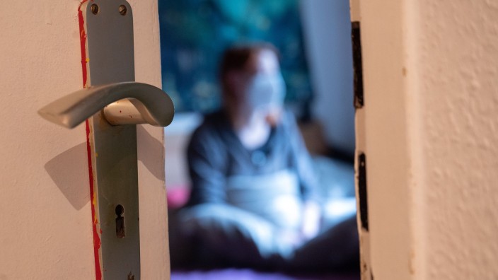 Pflegeberufe - Mainz: Eine Frau sitzt während der Isolation nach einem positiven Corona-PCR-Test auf ihrem Bett. Foto: Sebastian Gollnow/dpa/Symbolbild