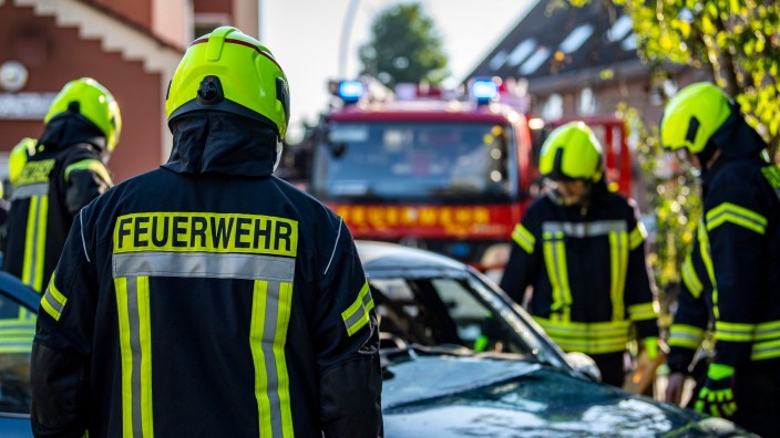 Brände - Berlin: Feuerwehrleute stehen um ein Auto, das einen Unfall gehabt hat. Foto: David Inderlied/dpa/Symbolbild