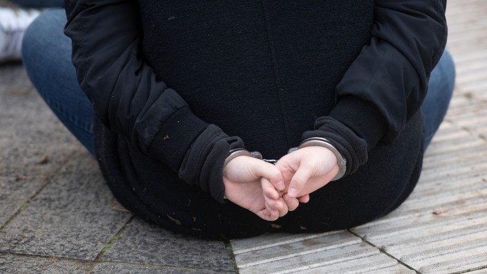 Kriminalität - Freiburg im Breisgau: Eine Aktivistin der Gruppe "Letzte Generation" sitzt mit Handschellen gefesselt auf einer Straße. Foto: Paul Zinken/dpa