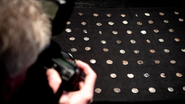 Archäologie - Aurich: Ein Fotojournalist fotografiert zahlreiche römische Münzen. Foto: Hauke-Christian Dittrich/dpa