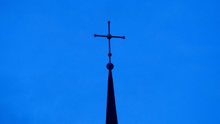 Kirche - Würzburg: Das Kreuz einer Kirche ist in der Abenddämmerung zu sehen. Foto: Friso Gentsch/dpa/Symbolbild