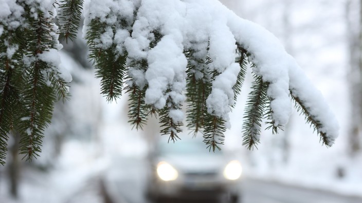 Wetter - Offenbach am Main: Ein Auto fährt hinter einem schneebedeckten Zweig über die Straße. Foto: Matthias Bein/dpa-Zentralbild/dpa/Symbolbild