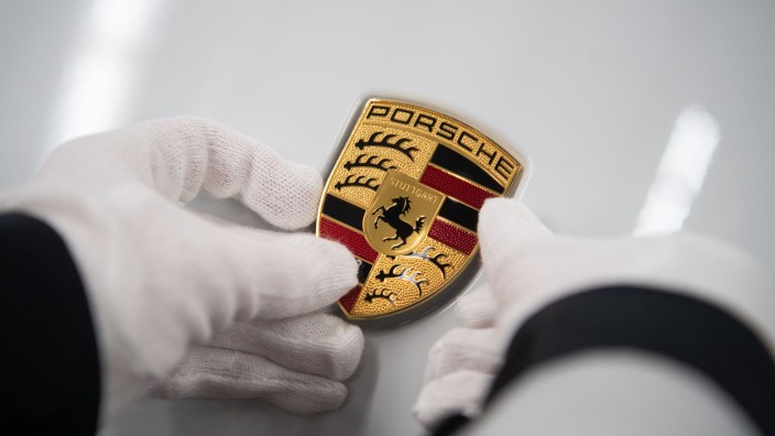 Börsen - Frankfurt am Main: Eine Mitarbeiterin der Porsche AG hält in der Produktion ein Porsche-Emblem. Foto: Marijan Murat/dpa/Archivbild