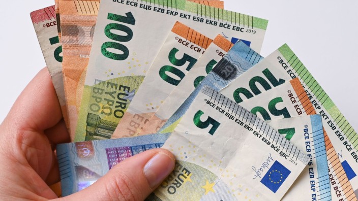 Einkommen - Schwerin: Eine Frau hält Geldscheine in der Hand. Foto: Patrick Pleul/dpa-Zentralbild/dpa/Illustration