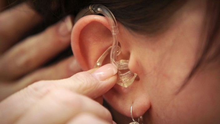 Soziales - München: Eine Hörgeräteakustikerin setzt ein Hörgerät in das Ohr einer Hörgeschädigten. Foto: picture alliance/dpa/Symbolbild