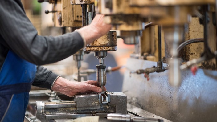 Mittelstand - München: Ein Mitarbeiter bedient in einer Produktionshalle eine Maschine zur Verarbeitung von Metall. Foto: Monika Skolimowska/zb/dpa/Symbolbild