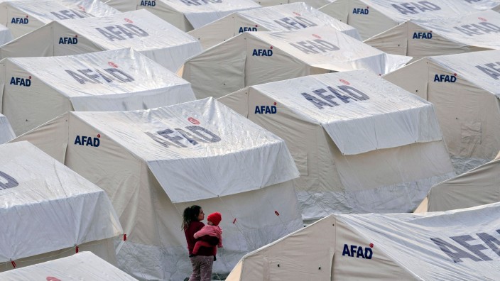 Katastrophen - Berlin: Eine Frau hält ein Kind zwischen Zelten auf dem Arm. Foto: Kamran Jebreili/AP/dpa