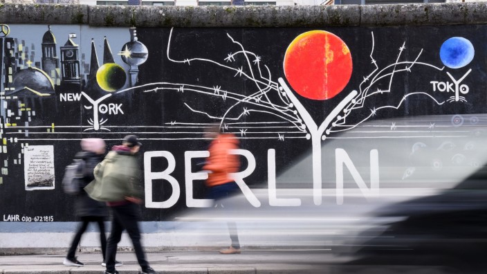 Tourismus - Berlin: Touristen gehen an einem Wandbild an der Eastside-Gallery vorbei. Foto: Bernd von Jutrczenka/dpa