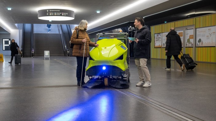 Technik - Ulm: Psychologe Johannes Kraus spricht in der Fußgängerunterführung am Hauptbahnhof neben einem Reinigungsroboter mit der sehbehinderten Gertrud Vaas. Foto: Stefan Puchner/dpa