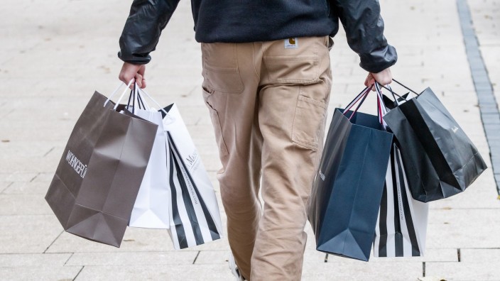 Einzelhandel - Burgwedel: Ein Mann geht mit Einkaufstüten durch die Innenstadt. Foto: Markus Scholz/dpa/Symbolbild