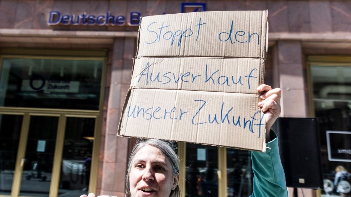 Banken - Berlin: Demonstrantin mit Schild "Stoppt den Ausverkauf unserer Zukunft" vor einer Deutschen-Bank-Filiale. Foto: Carsten Koall/dpa