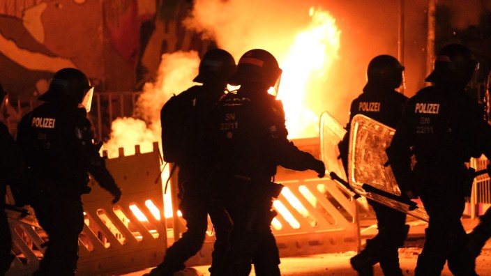 Demonstrationen - Leipzig: Polizisten gehen an einer brennenden Barrikade vorbei. Foto: Sebastian Willnow/dpa