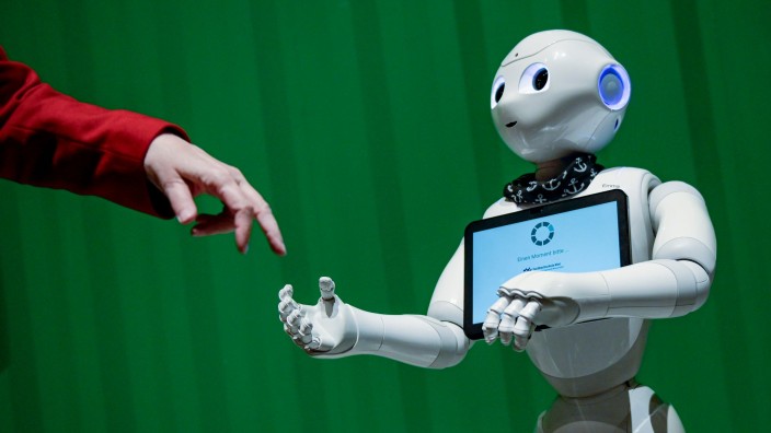 Computer - Hamburg: Ein Roboter interagiert mit einer Frau. Foto: Axel Heimken/dpa/Symbolbild