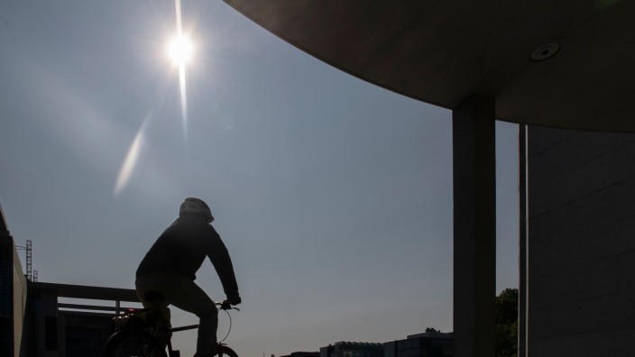Wetter - Berlin: Im Gegenlicht der Sonne ist im Regierungsviertel ein Radfahrer nur als Silhouette zu erkennen. Foto: Paul Zinken/dpa