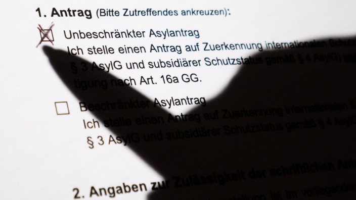 Ausländer - Mainz: Der Schatten eines Kugelschreibers zeichnet sich auf einem Asylerstantrag ab. Foto: Julian Stratenschulte/dpa/Illustration