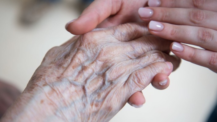 Kabinett - München: Eine Pflegerin hält die Hand einer Bewohnerin in einem Seniorenzentrum. Foto: Christophe Gateau/dpa