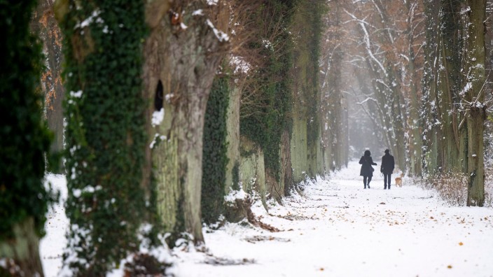 Wetter - Berlin: Ein Paar mit einem Hund spaziert bei winterlichem Wetter durch den verschneiten Park Sanssouci. Foto: Monika Skolimowska/dpa