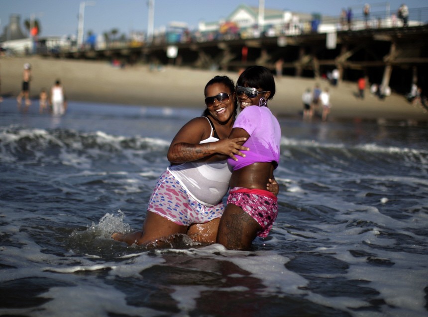 Symphony Taite and Keyanna Fowler dodge waves as they stay cool in the ocean in Santa Monica