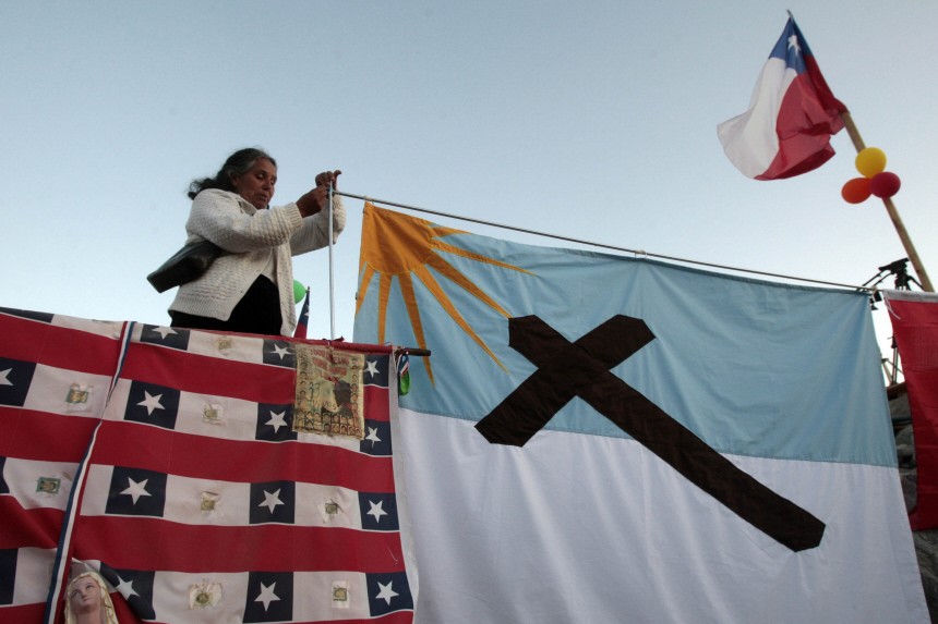 A relative of one of the 33 miners trapped deep underground in a copper and gold mine hangs a religious flag at San Jose mine