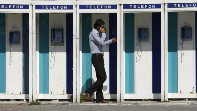 A man uses his mobile phone as he walks past public telephone boxes in Istanbul