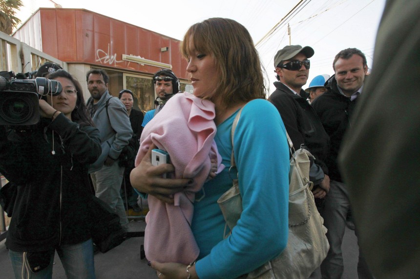 Elizabeth Segovia, wife of freed miner Ariel Ticona, walks past journalists to enter the Copiapo Hospital with her baby daughter