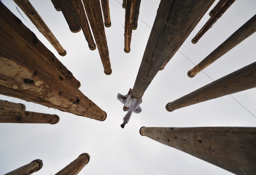 A man performs martial arts on the top of wooden totem poles during a show celebrating the Spring Festival at a park in Xiangfan