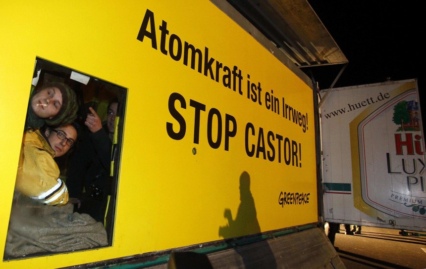 Activists of environmental organization Greenpeace look out of a container attached to a truck and the street as they block a key crossroad for the transportation of Castor nuclear waste containers in Dannenberg
