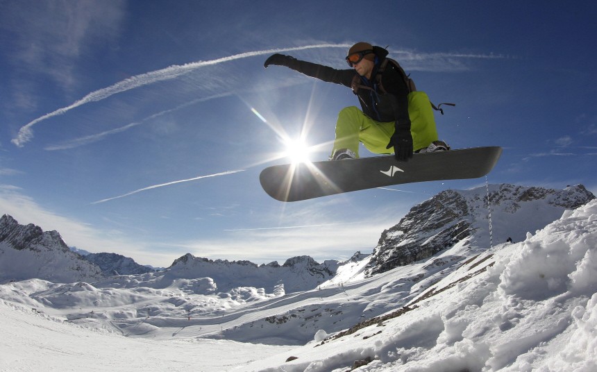 Snowboarder performs jump in front of Alps during winter season opening day at Zugspitze