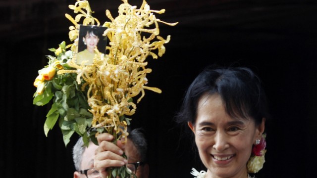 Aung San Suu Kyi holds a bunch of flowers before addressing supporters outside the headquarters of her National League for Democracy party in Yangon