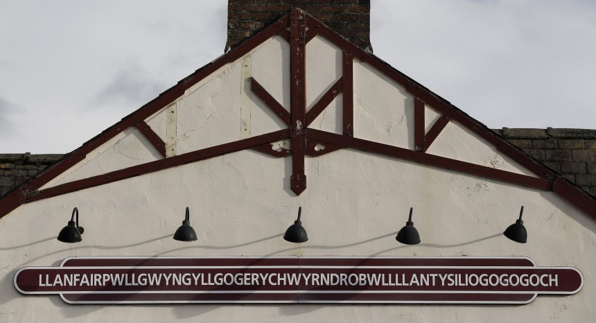 The name plate is seen on the side of the railway station building at Llanfairpwllgwyngllgogerychwyrndrobwllllantysiliogogogoch on Anglesey