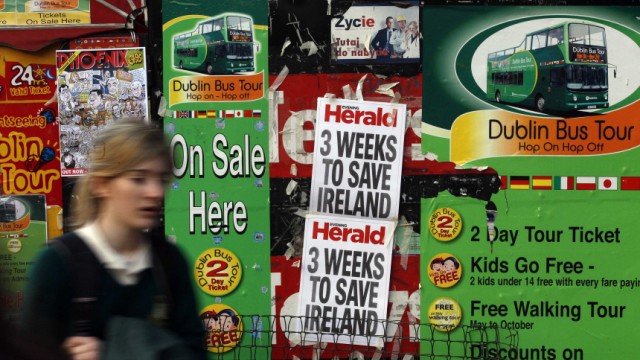 A woman walks past newspaper headlines posted on a news stand on O'Connell street, Dublin