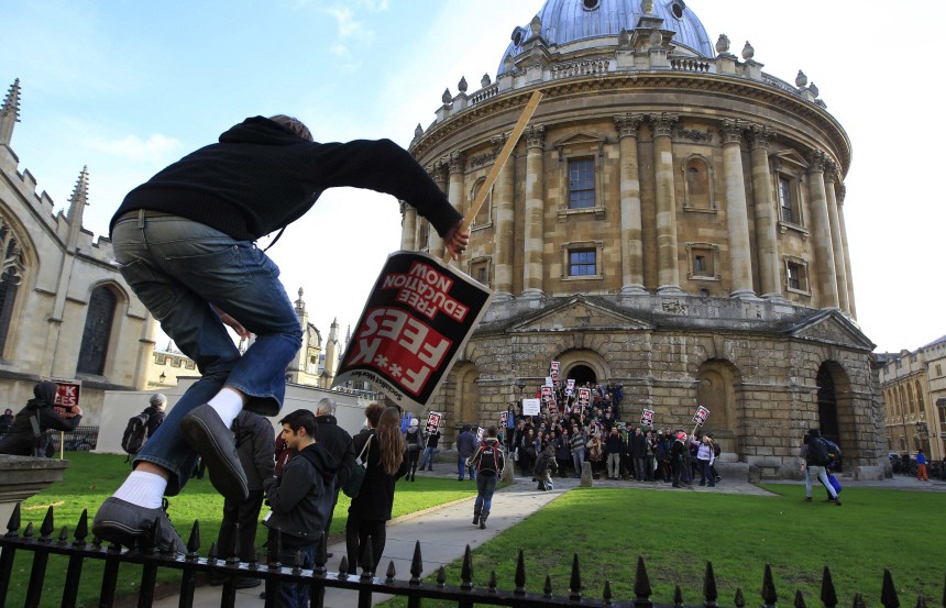 A student jumps over a fence to join other students occupying Oxford University's Radcliffe Camera building, in Oxford
