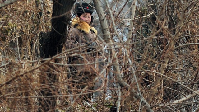 Korea-Krise: Die Rolle Chinas: Eine bewaffnete nordkoreanische Soldatin patrouilliert an der nordkoreanisch-chinesischen Grenze nahe des Yalu-Flusses.