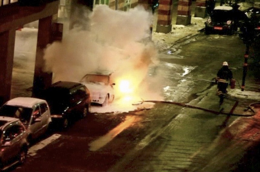 A still image taken from a video footage shows firefighter attempting to put out the fire on a burning car in Stockholm