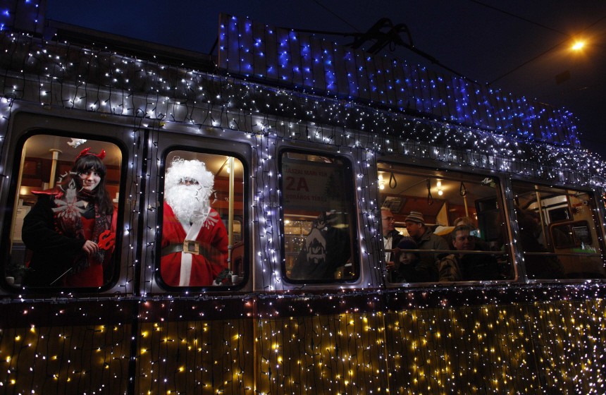 A man dressed as Santa Claus and a woman dressed as mythical creature Krampus travel in a tram decorated with Christmas lights in the centre of Budapest