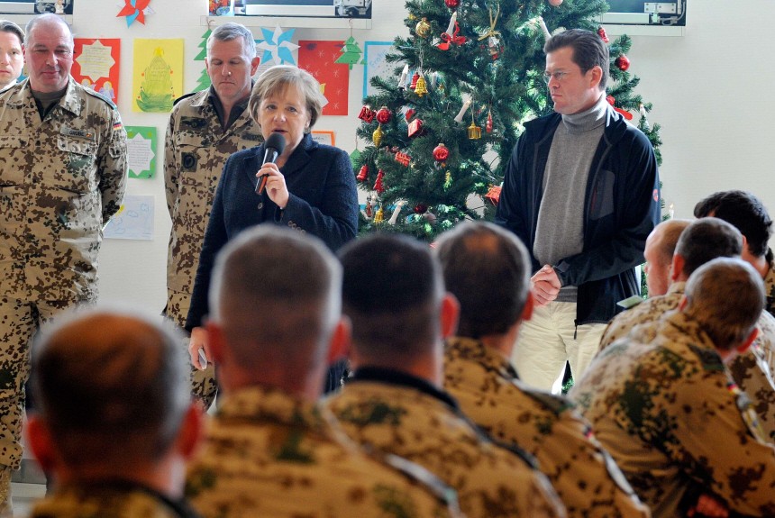 German Defence Minister zu Guttenberg and soldiers listen to Chancellor Merkel as she speaks during her visit to an army camp in Kunduz